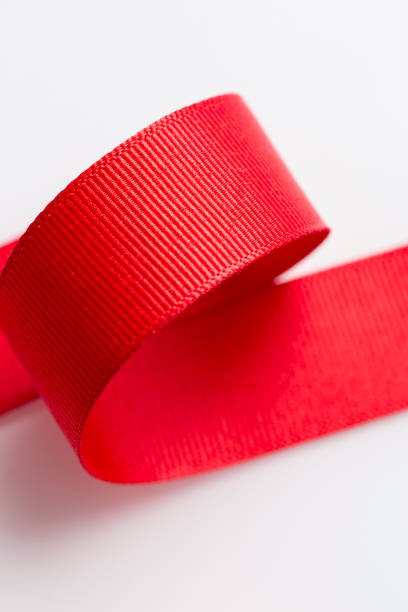 istock Macro Red ribbon textured with spiral roll isolated on white background 1214822732