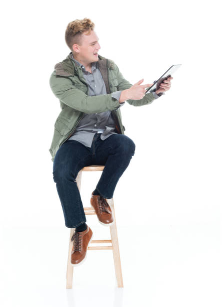 istock Caucasian boys resting in front of white background wearing pants and using digital tablet 1214822810
