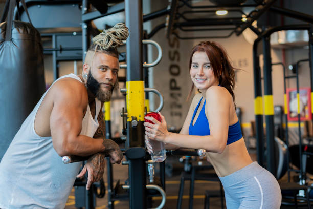 Beautiful multiracial Latino couple from Bogota Colombia between 20 and 29 years old look at the camera while in the gym and wear their sportswear