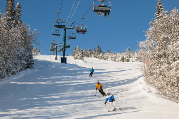 blick auf skifahrer auf skilift mit schneebedecktem bergsessellift über skipiste - abfahrtslauf stock-fotos und bilder
