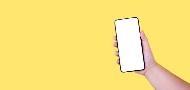 istock Hand holding Mobile. phone smartphone white screen on yellow background in studio With copy space. 1214835768