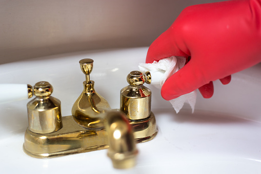 Hand in Red Plastic Gloves Cleaning Bath Faucet