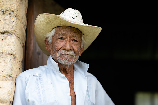 El Chorrito, Tamaulipas, Mexico, July 2, 2019: Mexican Senior, at his adobe home, waits by his door