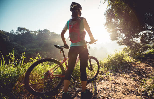 junge frau radfahrer genießen sie den wunderschönen sonnenaufgang auf sommer waldweg - freizeitaktivität im freien stock-fotos und bilder