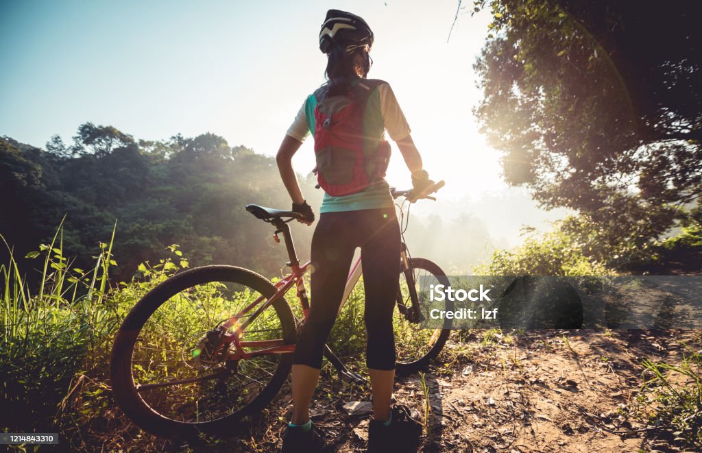 Young woman cyclist  enjoy the beautiful sunrise on summer forest trail Cycling Stock Photo