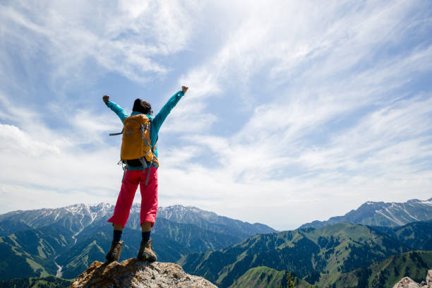 le randonneur fort de femme se tient aux bras de falaise sur le dessus de montagne - arms outstretched arms raised women winning photos et images de collection