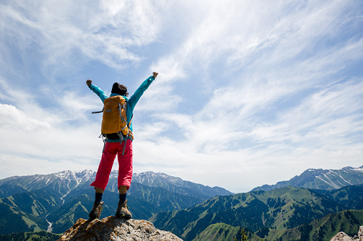 Strong woman hiker outstretched arms stand at cliff edge on mountain top