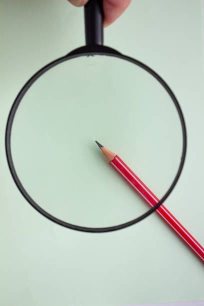 istock One red pencil under a magnifying glass close-up on a light background. 1214850508