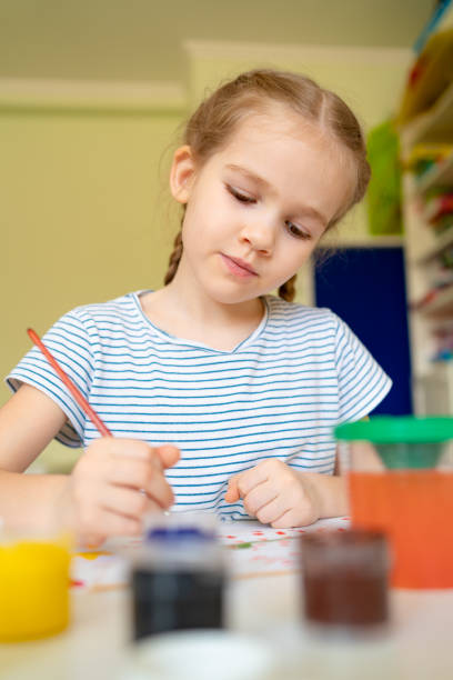 istock kid girl drawing with brush and paints 1214850608