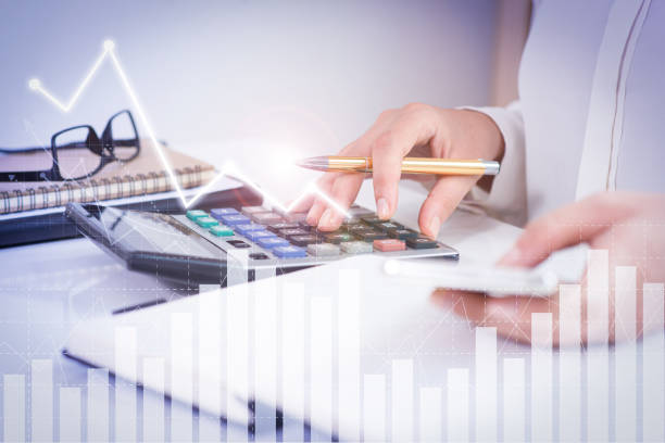 istock Woman using calculator and phone with financial analysis graphs 1214851714