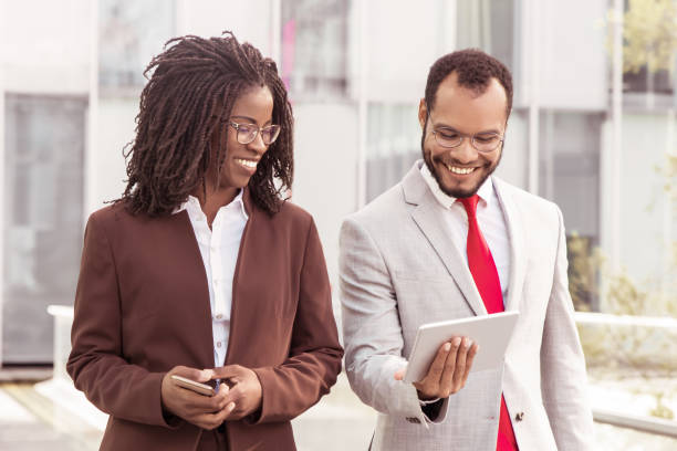 istock Cheerful business partners looking at tablet during stroll 1214853525