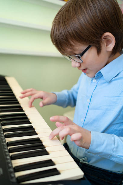 istock boy with glasses learns to play the synthesizer. 1214853936