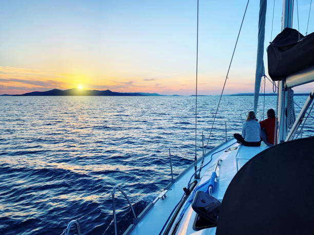istock Young couple enjoying sunset view at sailboat during sailing 1214854681