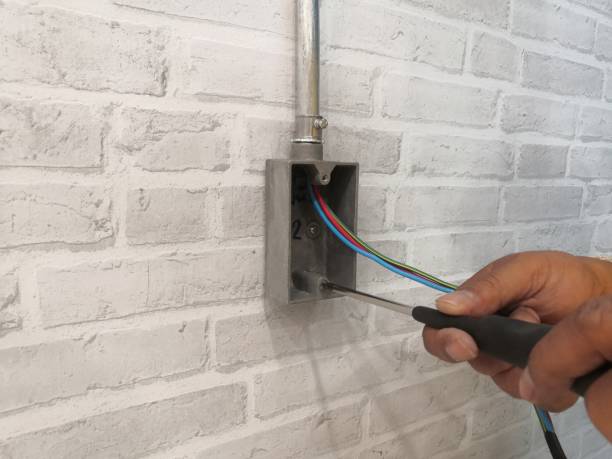istock Electrician installing F.S. BOX for electrical system work on gray brick wall.Technician installation electrical system work. 1214854865
