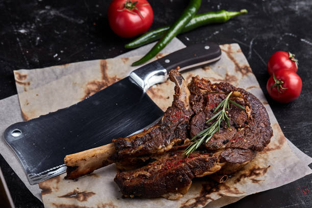 Tomahawk steak with vegetables and a knife on the table. Grilled meat with grilled vegetables and fresh vegetables on the table