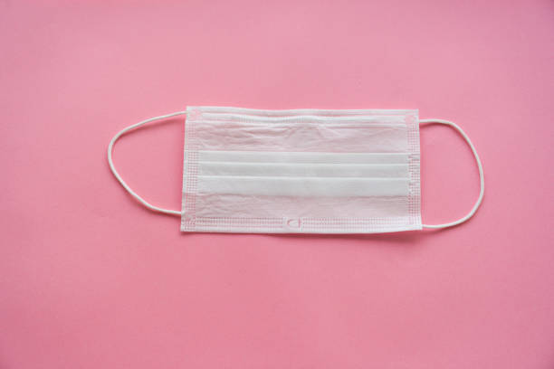 istock a disposable medical mask on a pink background. 1214855001