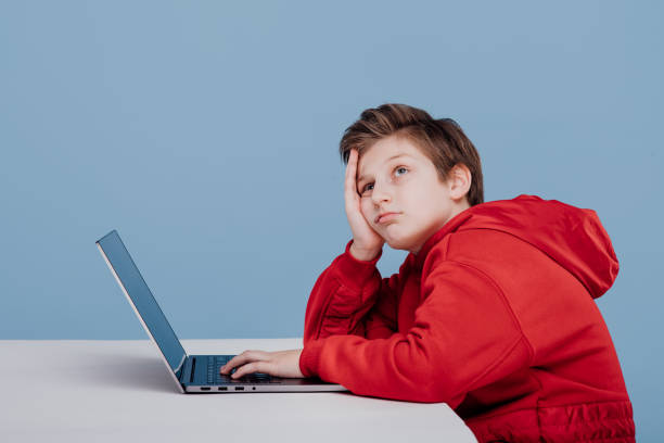 istock Bored preteen boy studying on laptop in studio 1214857336