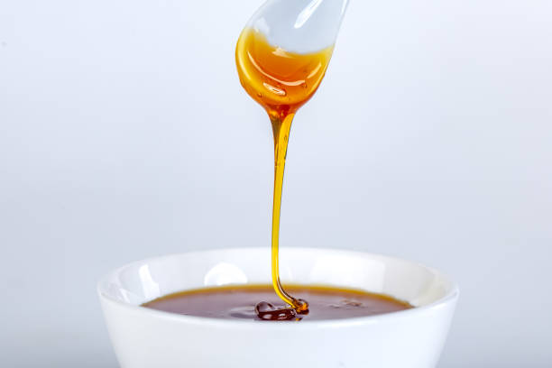 istock honey dripping from ceramic spoon to ceramic bowl 1214859279
