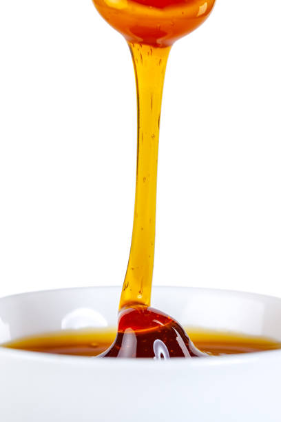 istock honey dripping from ceramic spoon to ceramic bowl 1214859315