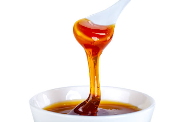 istock honey dripping from ceramic spoon to ceramic bowl 1214859390