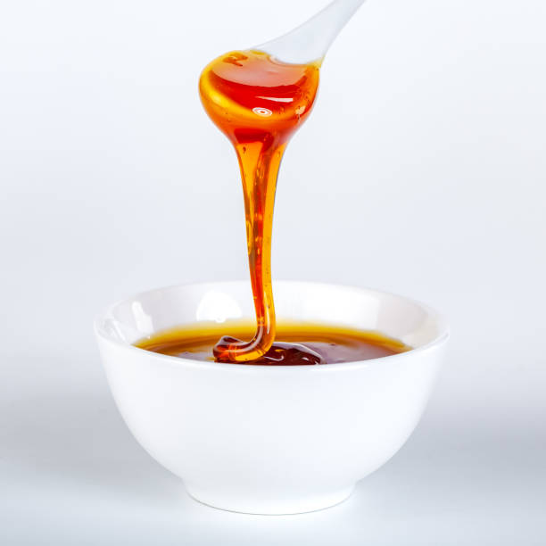 istock honey dripping from ceramic spoon to ceramic bowl 1214859547