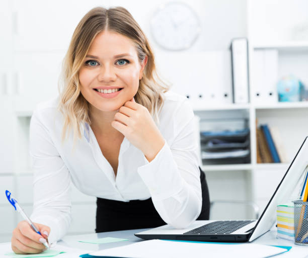 istock Mindful girl makes notes with pen in document on desk in well-lit office 1214861884