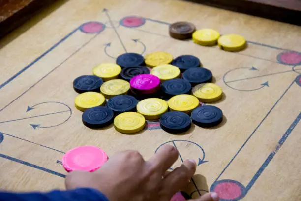 Photo of A game of carrom with pieces carrom man on the board carrom. Carom board game, selective focus.