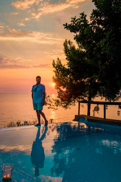 istock Fethiye Turkey, young guy in swim short watching sunset by the pool, mid age men by pool during vacation in Turkey 1214863407