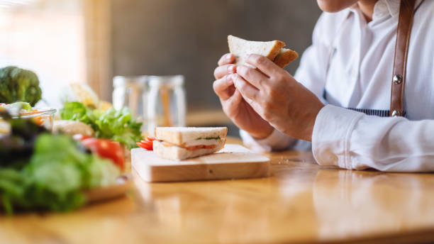 istock a female chef cooking and eating a whole wheat sandwich in kitchen 1214871355
