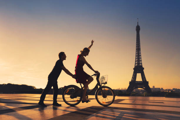 happy couple having fun in Paris riding bicycle near Eiffel tower happy couple having fun in Paris riding bicycle near Eiffel tower, silhouettes expatriate photos stock pictures, royalty-free photos & images