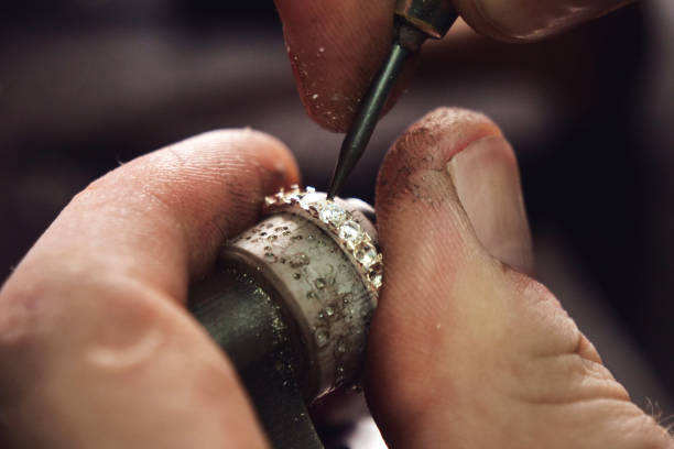 fermez-vous vers le haut de la main d’un or or ou d’argent ou d’un diamant utilisant des outils d’orfèvre. pour ce travail, il faut de la précision et de la patience - diamond jeweller jewelry examining photos et images de collection