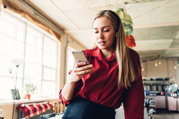 istock Young and handsome woman with mobile phone in hands standing in open space and reading message 1214875542