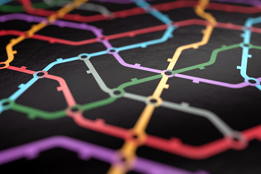Colorful metro scheme, railway transport or city bus map printed on black glossy paper surface. Close up macro view. Abstract 3D illustration