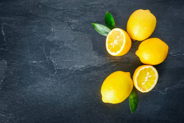 istock Fresh lemons on dark stone table. Ripe lemon from top view with green leaves 1214878531