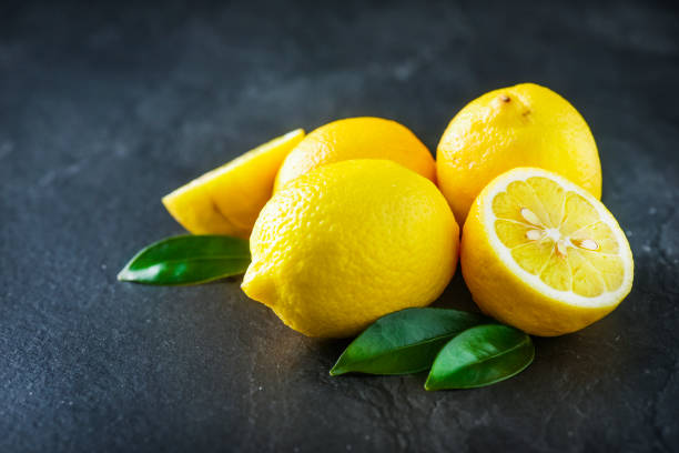 istock Fresh lemons on dark stone table. Ripe lemon from top view with green leaves 1214878557