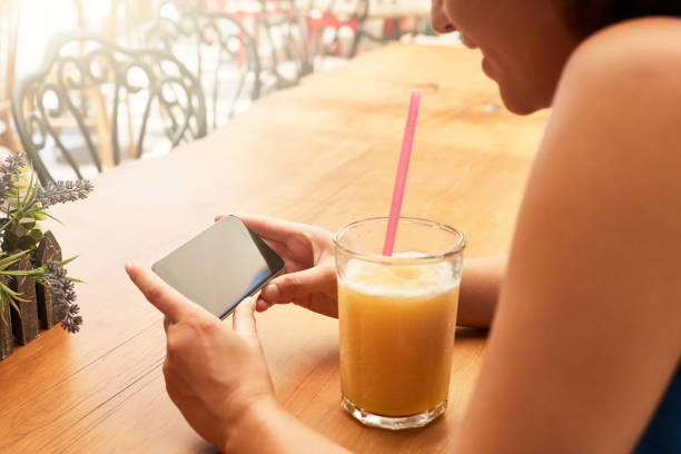 istock Woman holding smart phone with blank black screen in cafe 1214878559