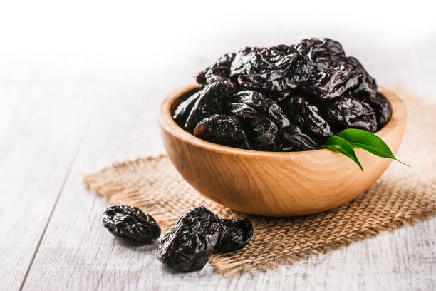 istock Prunes in wooden bowl on old rustic table. dried plums on table. 1214878592