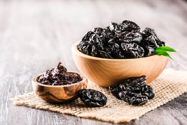 istock Prunes in wooden bowl on old rustic table. dried plums on table. 1214878618