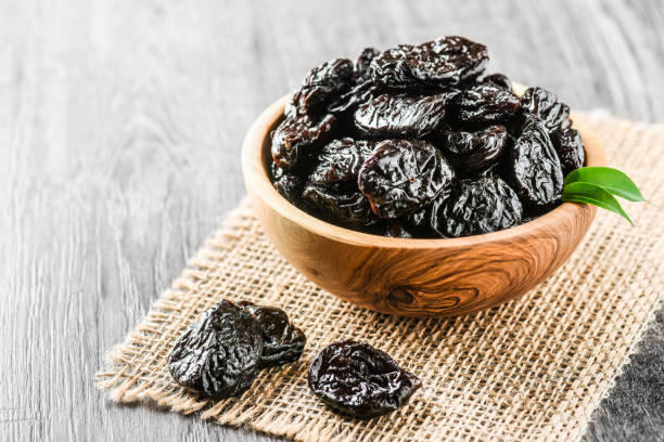 istock Prunes in wooden bowl on old rustic table. dried plums on table. 1214878644