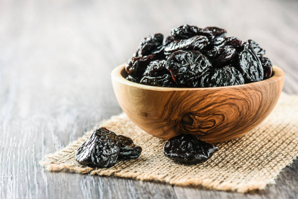 istock Prunes in wooden bowl on old rustic table. dried plums on table. 1214878651