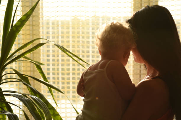 istock Mother with baby looking out the window. 1214879265