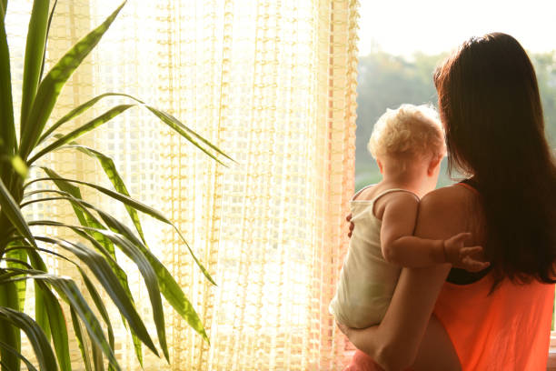 istock Mother with baby looking out the window. 1214879511