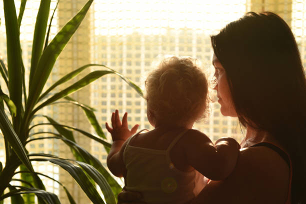 istock Mother with baby looking out the window. 1214881811