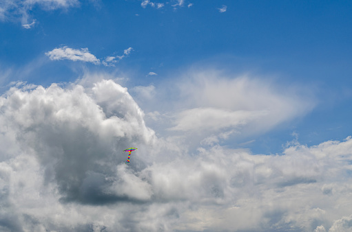 small flying kite on a background of clouds on a sunny summer day