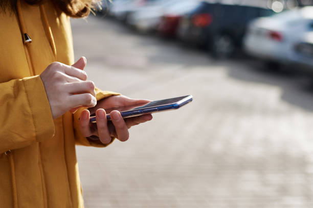 istock Midsection Of Woman Using Smart Phone While Standing Outdoors 1214884782