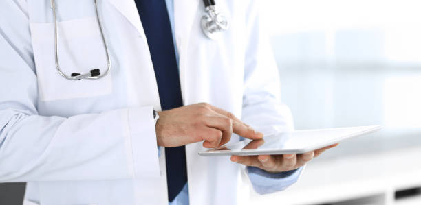 istock Doctor man using tablet computer for network research or virtual disease treatment, hands close-up. Perfect medical service in clinic. Modern medicine, medic data and healthcare concepts. Toned picture 1214886514