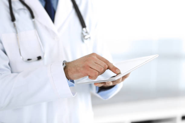 istock Doctor man using tablet computer for network research or virtual disease treatment, hands close-up. Perfect medical service in clinic. Modern medicine, medic data and healthcare concepts. Toned picture 1214886515