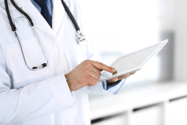 istock Doctor man using tablet computer for network research or virtual disease treatment, hands close-up. Perfect medical service in clinic. Modern medicine, medic data and healthcare concepts. Toned picture 1214886520