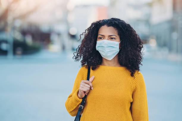 Young woman walking outdoors with a face mask Woman wearing a face mask walking outdoors avian flu virus photos stock pictures, royalty-free photos & images