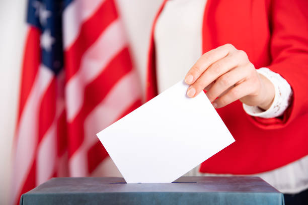 istock American voter putting ballot into voting box. 1214887506